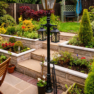 Well-maintained tiered garden with neatly pruned shrubs, weed-free stone beds, and a clean patio. Well-maintained tiered garden with neatly pruned shrubs, weed-free stone beds, and a clean patio.